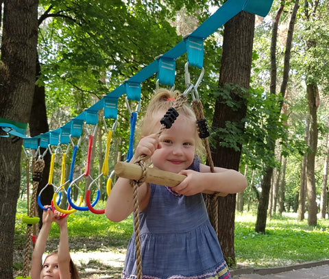 Kid playing on a Ground Anchored Rope Ladder For Kids, Kid-Friendly, 6.5 Ft Long By 16 In Wide in park setting.