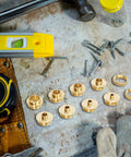 Front view: brass router template guide bushings set of 10 on a wooden bench with nails and a yellow level.