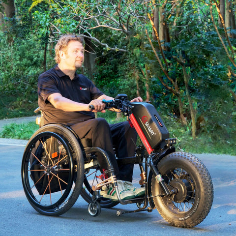 A8 Electric Handcycle Wheelchair Power Attachment Upgrade Kit in red, 48V 1000W, affixed to manual wheelchair on park path