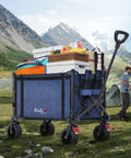 Collapsible Wagon Cart With Big Wheels And Brakes 250 Pound Capacity Lightweight Foldable Utility Wagon blue filled with camping gear on grass with mountains