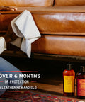 Leather Honey leather conditioner bottles beside a brown leather sofa; gray microfiber cloth in use.