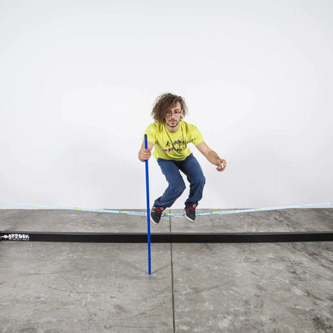 Person balancing on Slackhouse 3.0 Indoor Slackline Structure Built For Gym And Home Training with a blue pole.