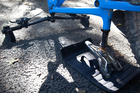 Bike on Flipstand Compact Bike Stand with Tool Storage, featuring saddle protector, handlebar stabilizers, on outdoor surface.