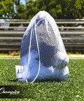 Breathable Mesh Sports Equipment Bag 12x18 Inch on grass, filled with sports gear, heavy duty nylon drawstring, ID tag visible.