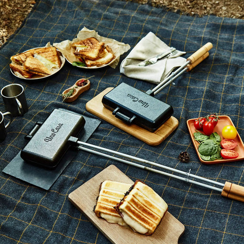 XL Cast Iron Pie Iron Sandwich Maker For Campfire Cooking with toasted sandwiches on a picnic blanket.