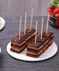 Cake bites with Bamboo Skewers 6 Inch 200 Pack For Appetizers, Fruit Kabobs on a white plate, strawberries in background