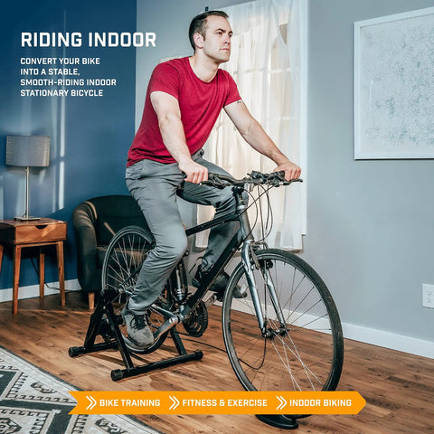Man using Indoor Bike Trainer Stand for Road and Mountain Bikes Portable Foldable Magnetic Stationary Trainer in living room