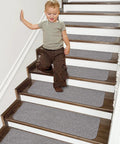 Child on stairs with Non Slip Stair Treads 15 Pack Carpet Mats For Indoor Stair Runners 28 By 9 Inches Grey 100 Percent Polyester With TPE Backing Protect Floors And Keep Kids And Pets Safe.