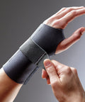 Left Hand Compression Wrist Brace With Three Adjustable Straps For A Custom Fit And Moderate Support Lets Your Fingers Move Naturally Easy To Use Black Size L/XL worn on a hand and being adjusted.