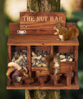 Wooden Squirrel Picnic Table Feeder With Multi Compart ment Seed Storage And Five Level Bar Stools Durable Outdoor Squirrel Feeder For Corn Cobs And Mixed Seeds Stable Table Style Wildlife Feeder 12.2 X 6.6 X 12.2 Inches on a tree trunk with squirrels eating.