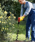 Man using Heavy Duty 3 Inch By 24 Inch Garden Auger Drill Bit For Planting And Post Hole Digging with yellow flowers nearby.