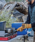 Person wearing Ranchworx Winter Work Gloves RWDI Premium Leather Insulated Cold Weather Gear using camping stove outdoors.