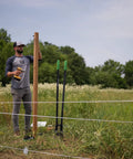 Man using Beefy Post Hole Digger With No Slip H Grip Handles, Rugged Fiberglass Core for fencing in a field.