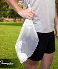 Person holding Breathable Mesh Sports Equipment Bag 12x18 Inch with baseballs on grassy field