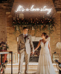 Wedding scene with couple under It's a Love Story Personalized Neon Light Sign For Bedroom And Wedding Decor Large 23.6 Inch LED