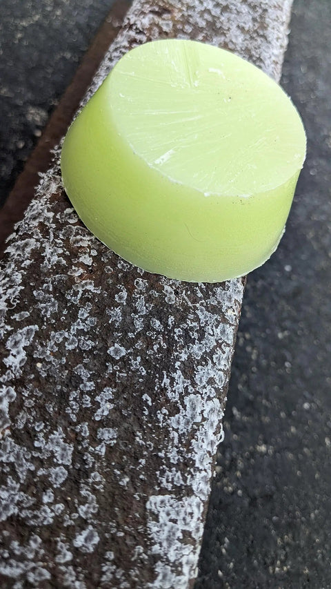 Lime green 70g premium skateboard wax on a curb, made in the USA with Nag Champa scent for smooth grinds, high-quality paraffin blend.