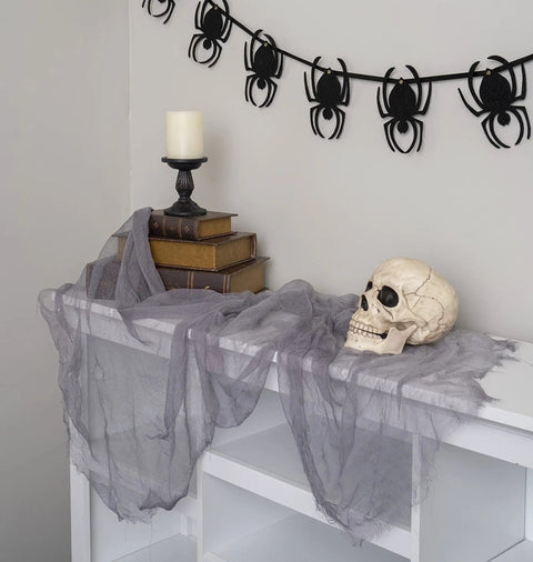 Six Inch Realistic Skeleton Skull Prop With Movable Jaw on draped table with books and candle