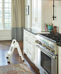 Two Step Folding Foot Stool, 14 Inch High, 300 Pound Capacity, in a kitchen near stove, rust and dent resistant design.