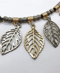 Leaf-shaped metal pendants with gold and silver tones on a beaded necklace.
