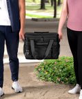 A couple holding the Epically Spacious Collapsible Soft Cooler Bag, 60 Can Leakproof Insulated Tote in a park setting.