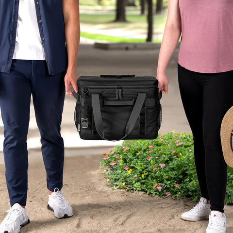 A couple holding the Epically Spacious Collapsible Soft Cooler Bag, 60 Can Leakproof Insulated Tote in a park setting.