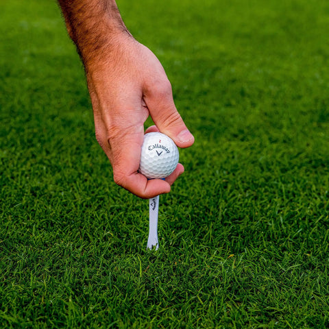 Premium Slick Rubberized Golf Tees With Durable Plastic Base For Low Spin Launch Assorted Colors 4 Pack in use with a golf ball.