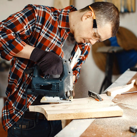 Person using a jigsaw in workshop wearing Unisex Brown Jersey Work Gloves 10 Inch Pack Of 24 Pairs Breathable Polyester Cotton Knit Wrist