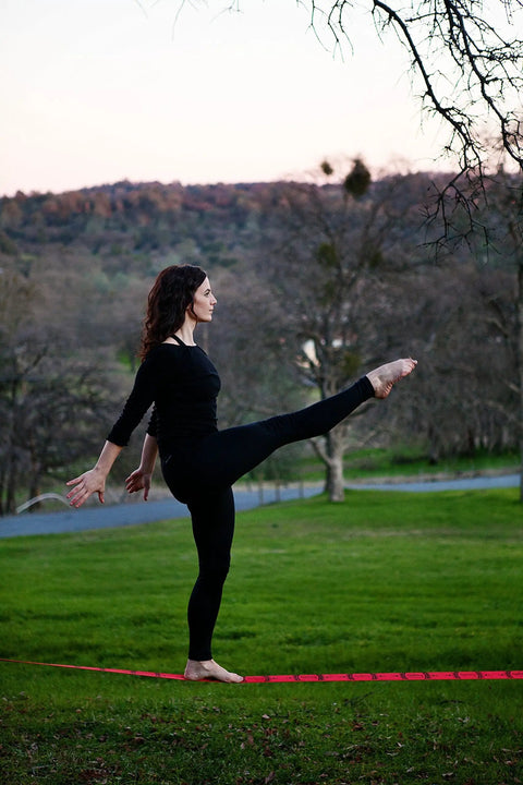 Person balancing on Slackline Kit With Overhead Training Line in a park setting.