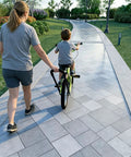 Parent guiding child on bike using Kids Bike Trainer Handle For Learning To Ride, Extended 21 To 30 Inch Balance Push Bar, Four Stage Height