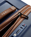 Close-up of Delsey 26-inch spinner luggage with navy blue basketweave texture, brown faux leather accents, TSA lock, and zippers.