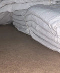 Stack of 2500 Count White Shop Towels For Mechanics, Industrial Grade 14x14, 100 Percent Cotton Rags, folded on a surface