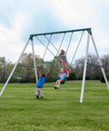 Children playing on Big Brutus Galvanized Steel Swing Set Kit With Classic A Frame Two Belt Swings Trapeze Bar Easy Assembly.