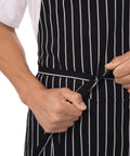 Person tying waist of durable unisex kitchen apron with reinforced stress points and comfy waist tie for men and women.