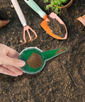 Hand holding Compact Handy Seed Spreader Handheld Planter Tool For Tiny Seeds Portable Mini Garden Seeder over soil