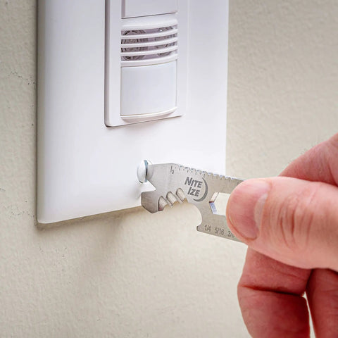Hand using DoohicKey Keychain Multi Tool Stainless Steel 8 In 1 Bottle Opener Nail Puller Wrench Ruler on light switch