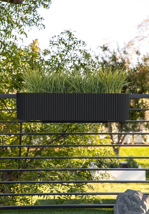 Badass Weatherproof Railing Planter Box With Secure Mounting Bracket, 36x8.5 inches, black, holding grass, mounted on a railing outdoors.