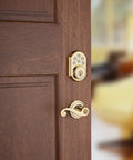SmartCode 910 Z Wave Plus Deadbolt With Keyless Entry And Illuminated Keypad on wooden door, polished brass finish