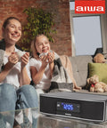 Two people enjoying music from Exos Home Speaker With 30W RMS Power, Bluetooth Streaming, CD Player, FM Radio on a coffee table.