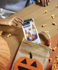 Child holding 24 Piece Halloween Magnetic Building Tiles For Kids To Build A Mini Haunted House, with candies and pumpkin.