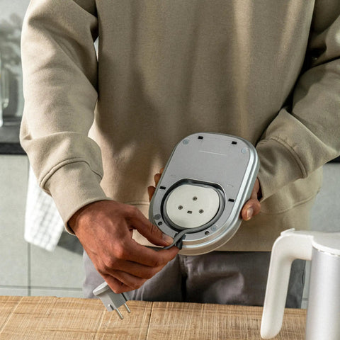 Person assembling base of Cool Touch 1 Liter Cordless Electric Kettle With Double Wall Stainless Steel Keeps Water Hot Longer And Exterior Cool 70 Degree Lid Opening For Steam Safety Compact Silver Teakettle For Small Kitchens Fast Boil Easy Pour