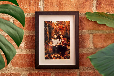 Photo Frame Diversion Safe With Hidden Compartment 4x6 Black Mini Safe Box hangs on a brick wall, displaying a family photo.