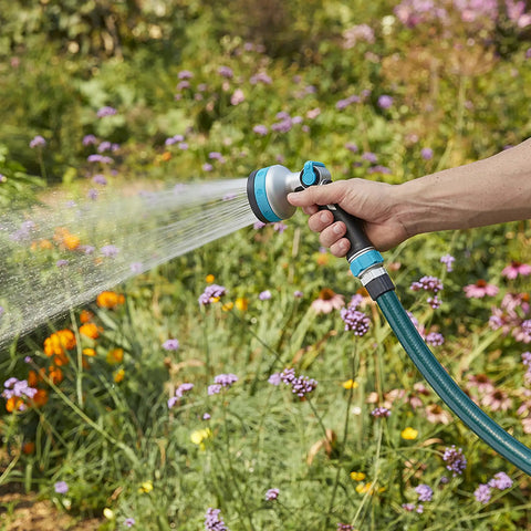Person using Heavy Duty Thumb Control Garden Hose Nozzle With Eight Pre Set Spray Patterns on flowers in garden