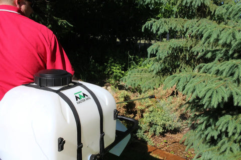 Person using 9 Gallon UTV And ATV Spot Sprayer with Everflo 1.0 GPM Diaphragm Pump for tree spraying in a garden.