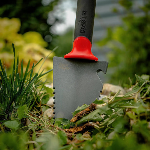 All In One Garden Trowel With Holster For Digging Planting And Root Cutting Serrated Steel Blade in garden soil close-up