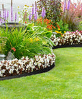 No Dig 4 Inch Landscape Edging Kit 33 Feet Long With 30 Spikes Flexible Garden Border curves around flower beds in a garden.