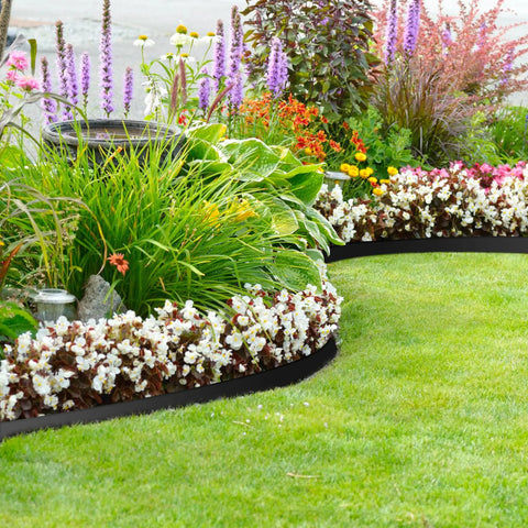 No Dig 4 Inch Landscape Edging Kit 33 Feet Long With 30 Spikes Flexible Garden Border curves around flower beds in a garden.
