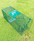 Foldable humane live animal cage trap kit 26 inch no kill catch and release two door on grass, heavy duty steel mesh, green