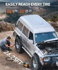 Man using Trail Ready Portable Air Compressor Bad Boy 12 Volt Tire Inflator on SUV tire with 26 ft hose at outdoor site.