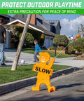 Kids At Play Street Safety Sign With High Visibility Neon Orange Design, All Weather Durability, Includes Warning Flag To Slow Down Drivers And Keep Pedestrians Safe placed on street corner near playing kids