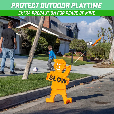 Kids At Play Street Safety Sign With High Visibility Neon Orange Design, All Weather Durability, Includes Warning Flag To Slow Down Drivers And Keep Pedestrians Safe placed on street corner near playing kids